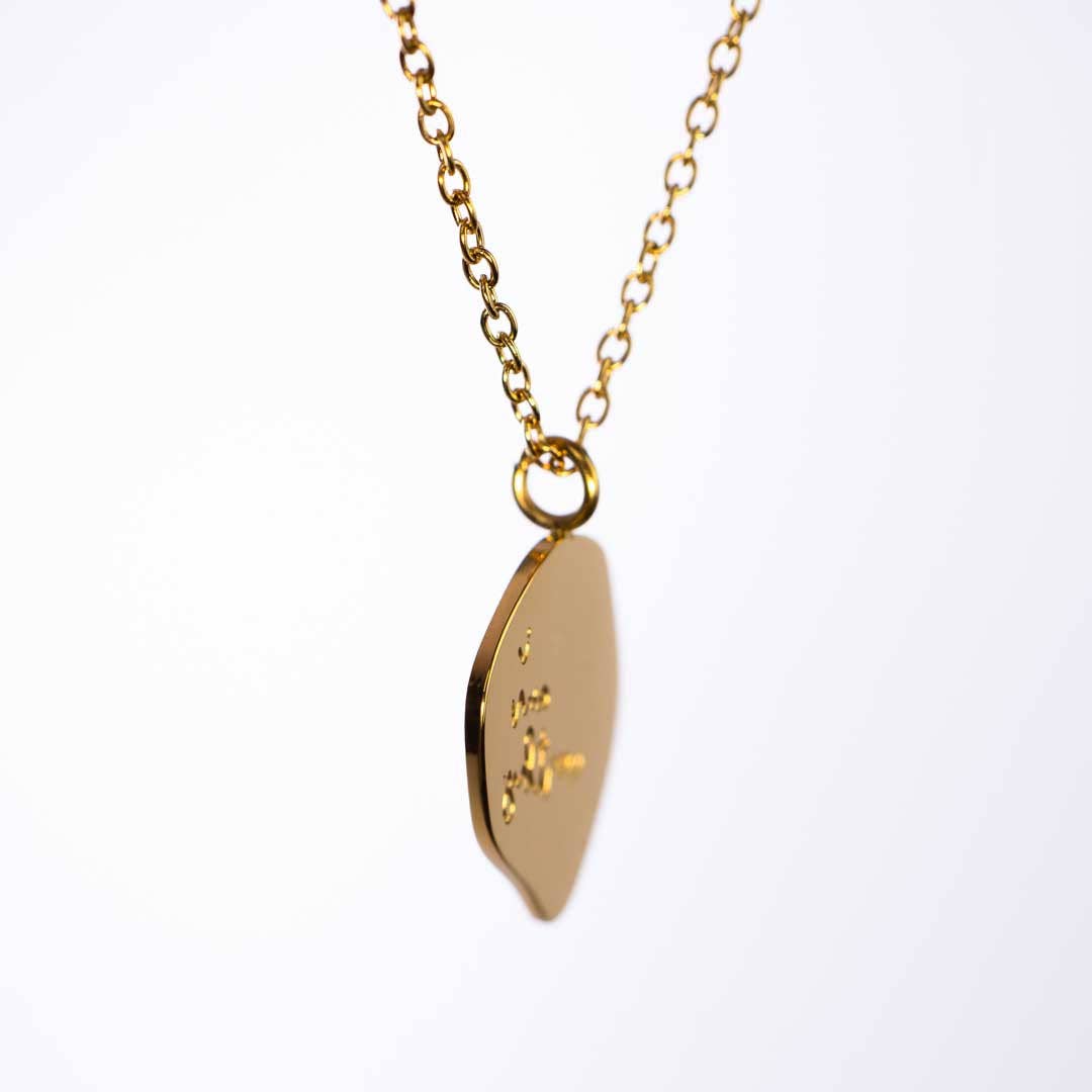 Gold necklace with a leaf-shaped pendant on a white background