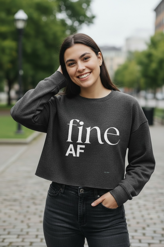 Woman wearing a black sweatshirt with 'fine AF' text outdoors.