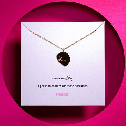 Necklace with pendant on a card against a pink background