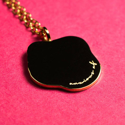 anxious af text engraving on a pendant with gold chain on pink background