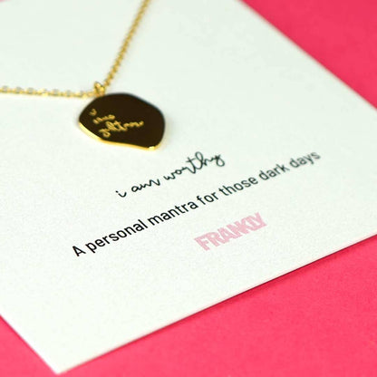 Necklace with a pendant on a card with text and branding