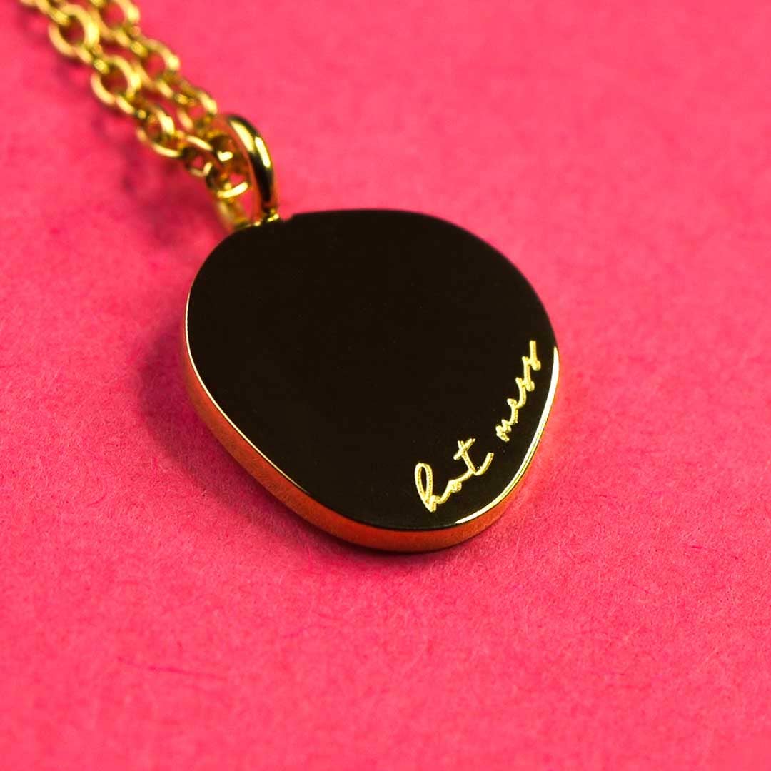18k Gold heart-shaped pendant with Hot Mess Text on a pink background