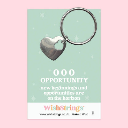 Heart-shaped keychain on a WishStrings branded card with motivational text on a pink background
