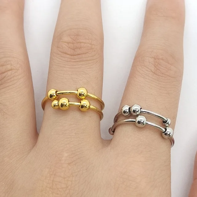 Two gold and silver rings on a person's fingers against a white background
