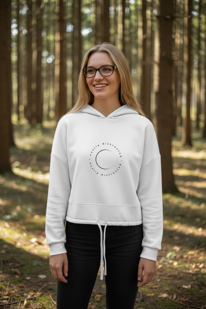 Woman wearing a white hoodie with a logo in a forest