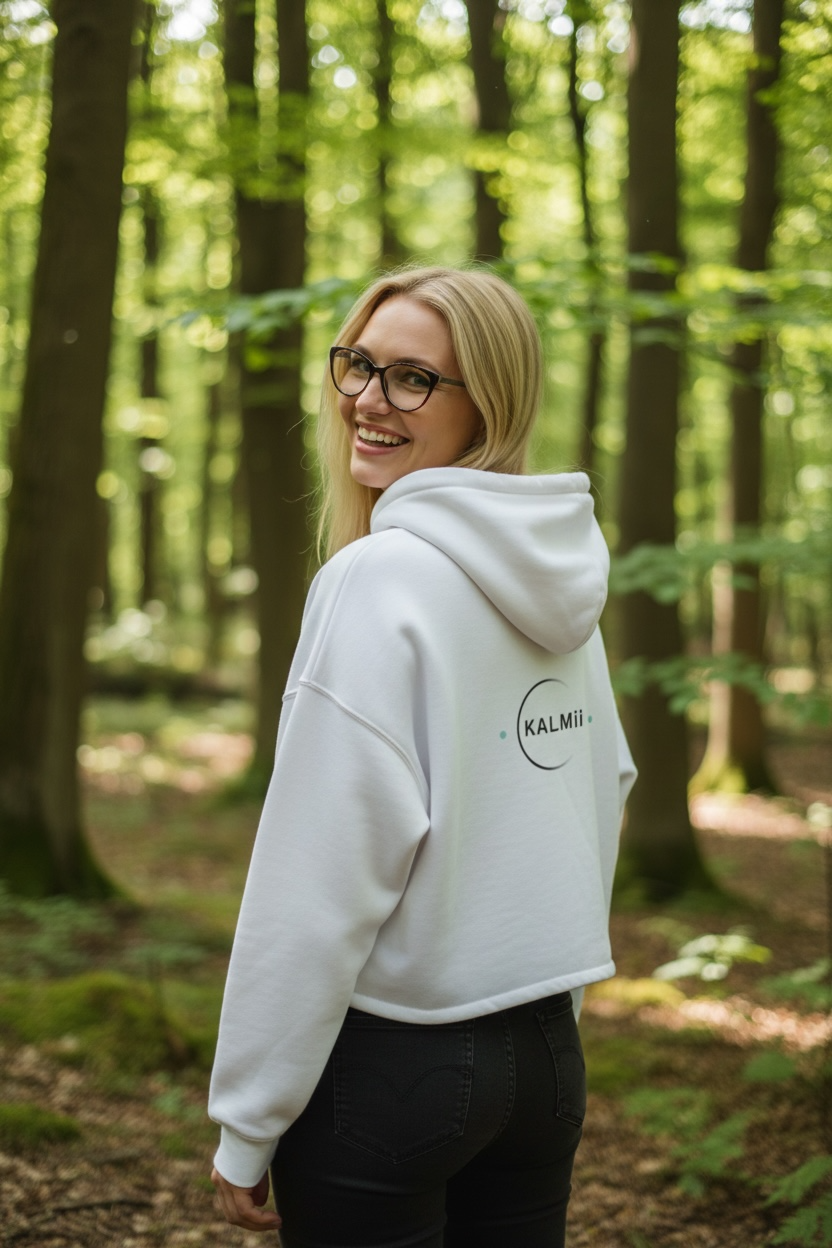 Person wearing a white hoodie with 'KALMii' logo in a forest setting