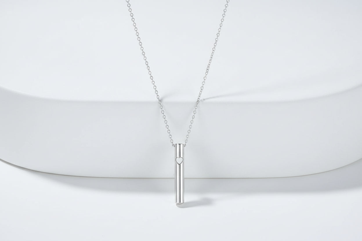 Silver necklace with a cylindrical pendant on a light gray background