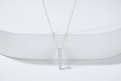 Silver necklace with a cylindrical pendant on a light gray background