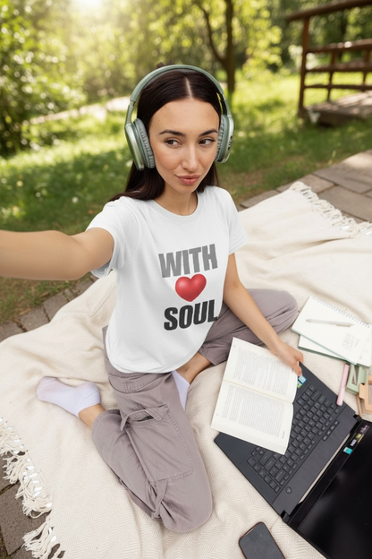 Woman sitting outdoors with headphones on, using a laptop and holding a book wearing KALMii 'WITH SOUL' Tee
