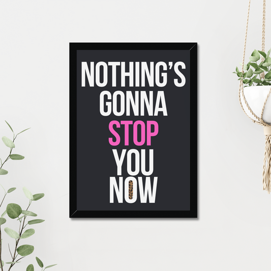 Framed poster with motivational quote 'Nothing's Gonna Stop You Now' on a white wall with plants.