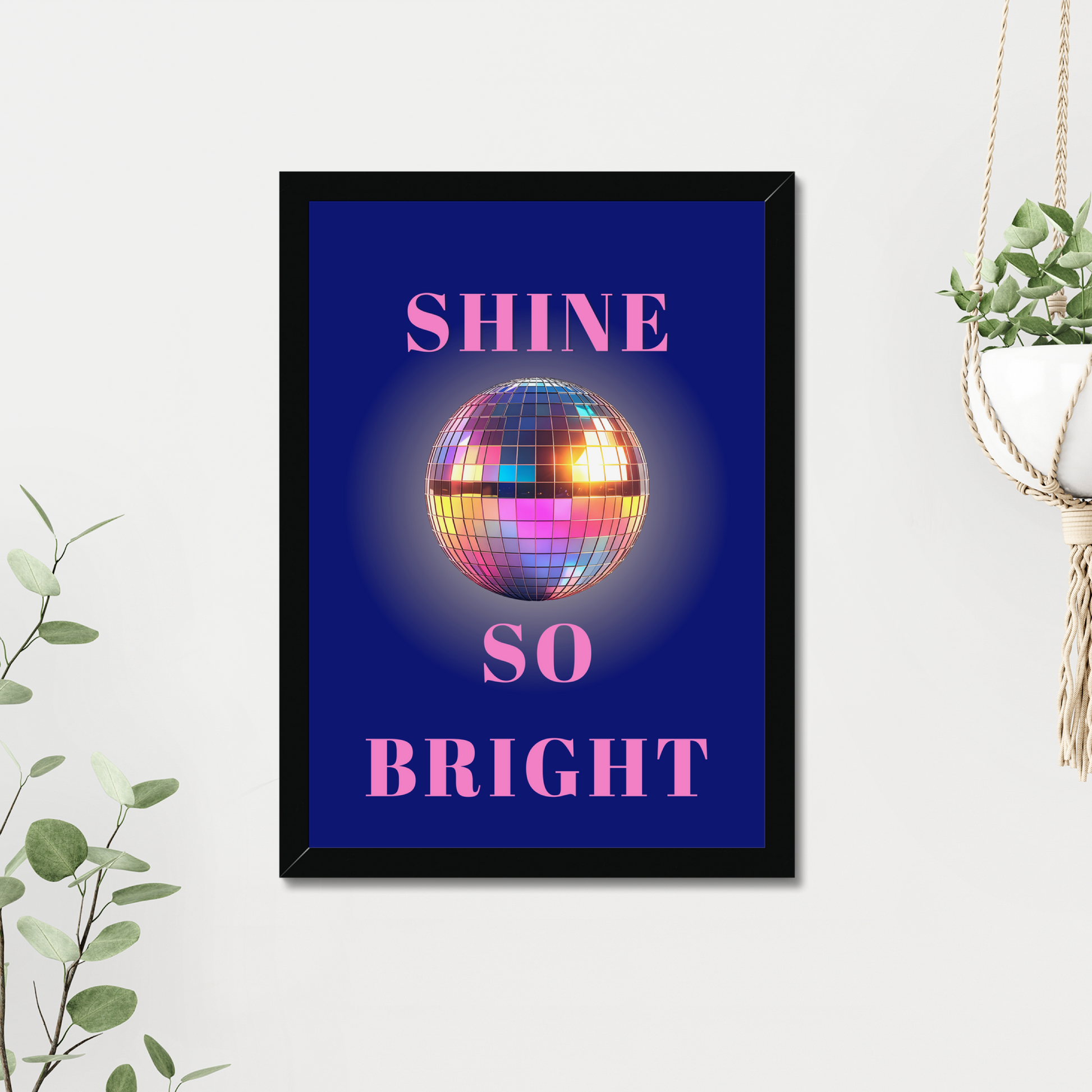 Framed poster with disco ball and 'Shine So Bright' text on a white wall.