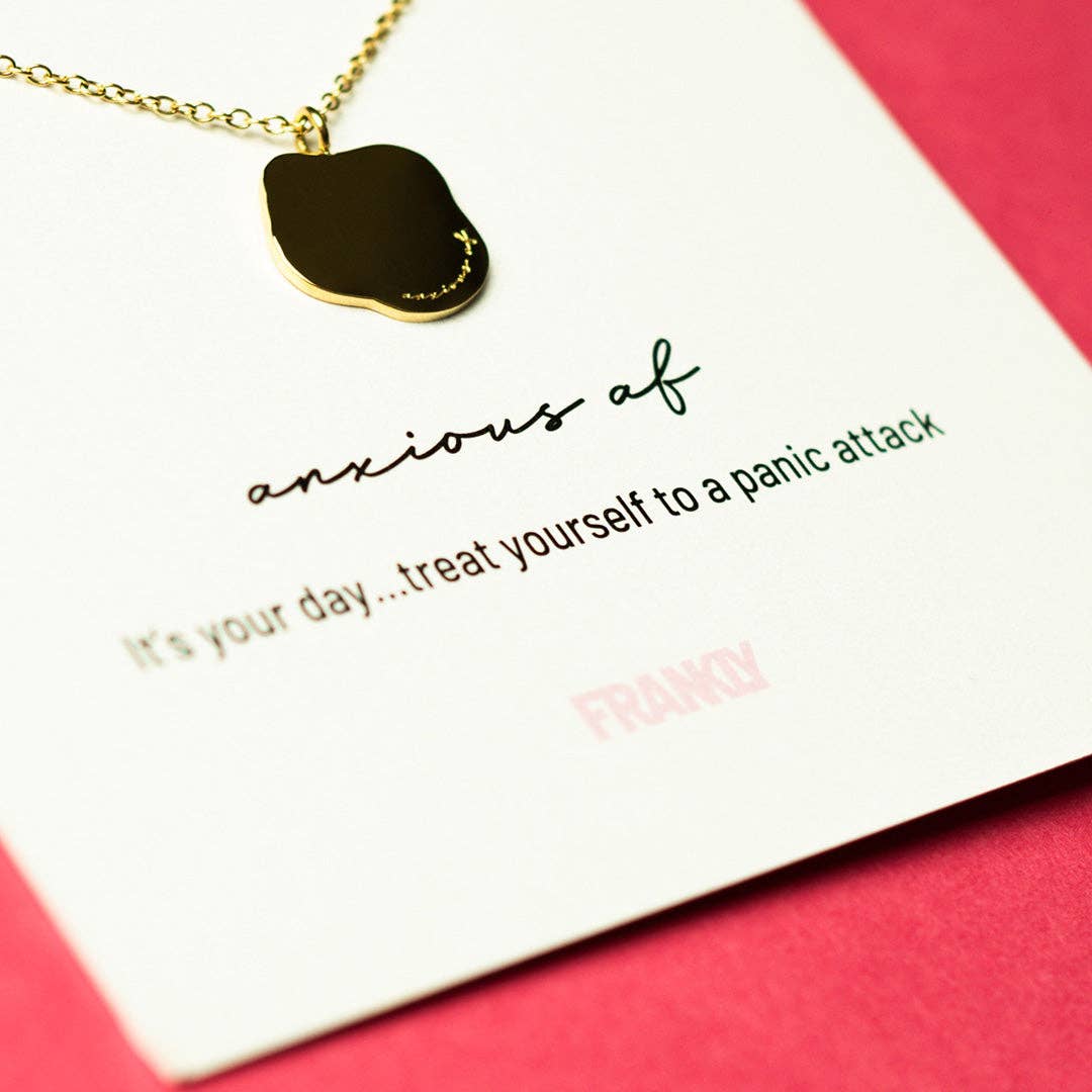 Necklace with a gold pendant on a card with humorous text, against a pink background
