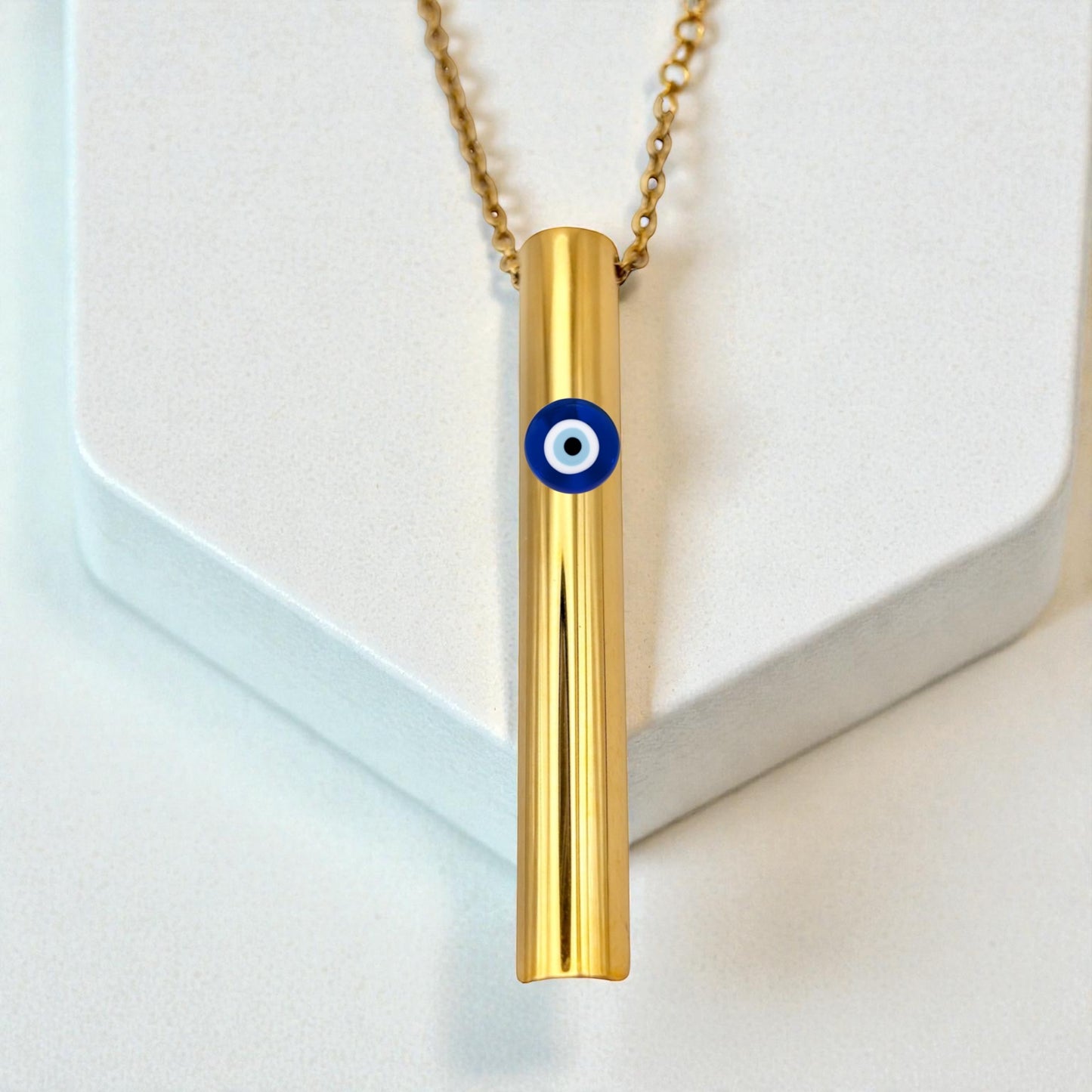 KALMii Gold necklace with a cylindrical pendant featuring an evil eye design on a white background Anxiety necklace